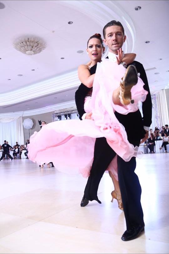 Jaklyn Royal and her partner dancing beneath chandeliers in an elegant ballroom