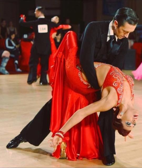Jaklyn Royal in a red gown performing a dramatic dip at a ballroom competition